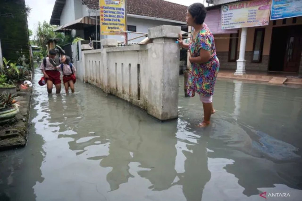 Dua siswa berjalan di lorong gang lingkungan rumahnya yang tergenang banjir bercampur limbah industri di Desa Sidorejo, Tulungagung, Jawa Timur, Kamis (27/10/2022)
