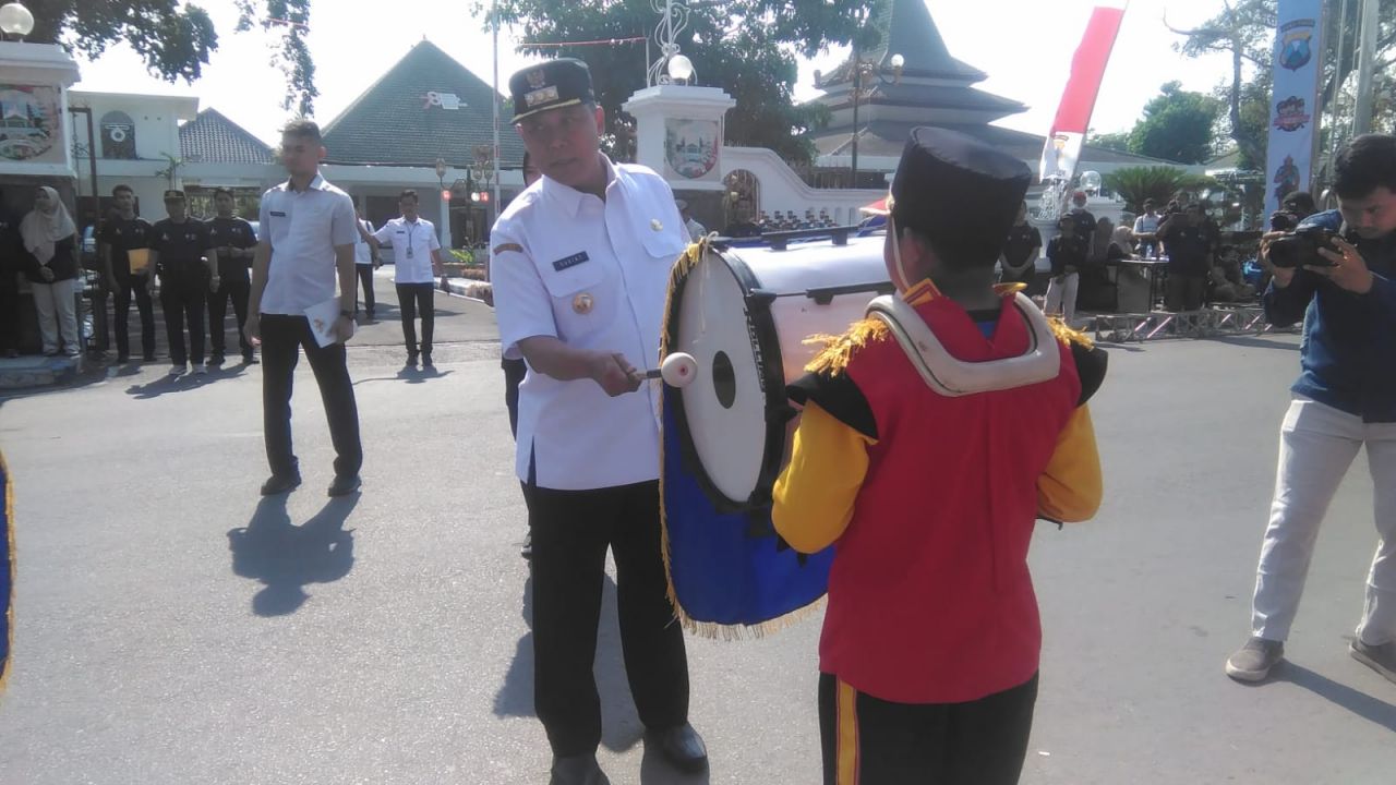 Simbolis : Pj Bupati Jombang Sugiat, S.Sos.,M.Psi., didampingi Kapolres Jombang AKBP. Eko Bagus Riyadi secara simbolis membuka lomba pawai Drumband Kapolres Cup 2023 di alun-alun Jombang dengan memukul Bass Drum