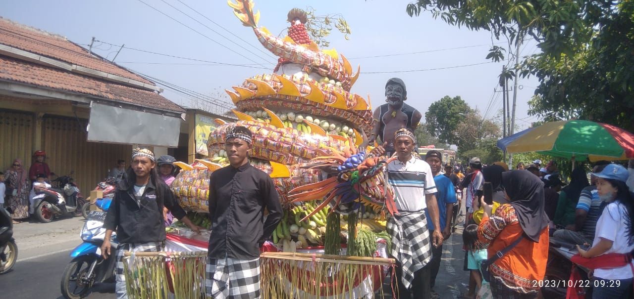 Lilit : Patung naga raksasa yang melilit tumpeng, menarik perhatian warga yang sedang menikmati pawai budaya dalam gelaran sedekah desa Kedungdowo
