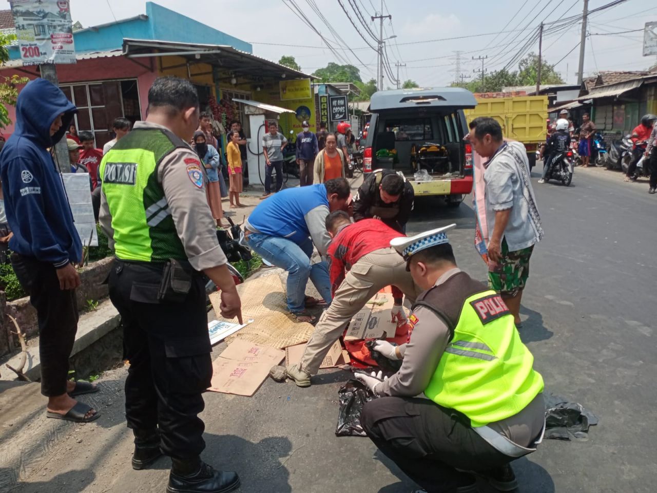 Evakuasi : Petugas Laka Lantas Polres Mojokerto, dibantu warga mengevakuasi jasad korban untuk di masukkan ke dalam mobil ambulance