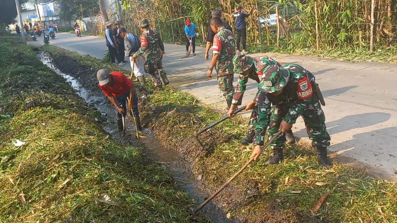 Kompak : Anggota Koramil 1907/BGS bersama masyarakat dan aparatur desa bahu membahu membersihkan selokan yang tesumbat sampah dan sedimen lumpur