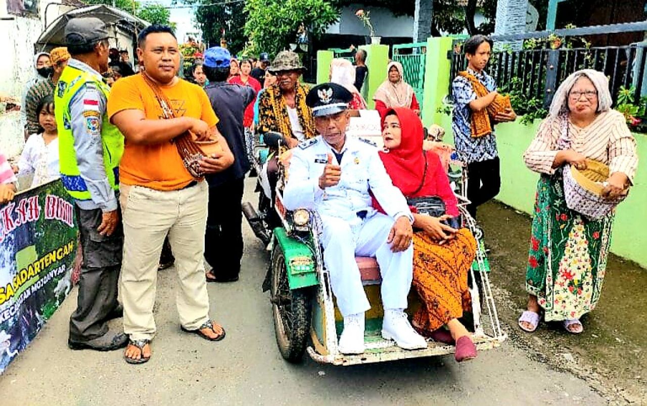 Partisipasi : Kades Sadartengah Muji Utomo bersama Istri saat mengikuti kirab gunungan menggunakan kendaraan roda tiga (becak)