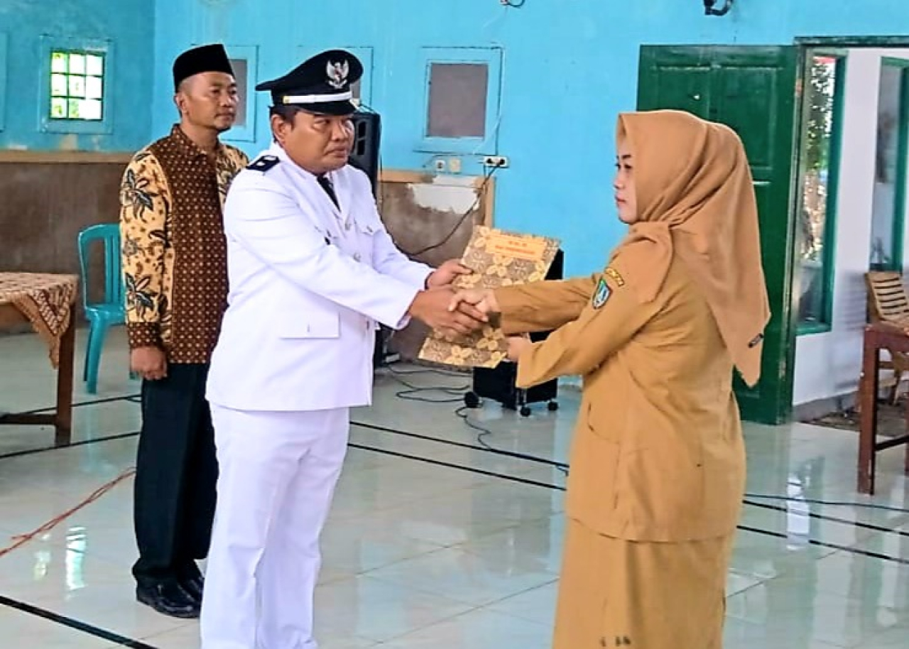 Kades Sudimoro Romy Fatawi saat menyerahkan SK pengangkatan Kasi Pemerintahaan yang dijabat oleh Bella Wahyu Nurshokib (foto : lekdar_beritaformat.com)