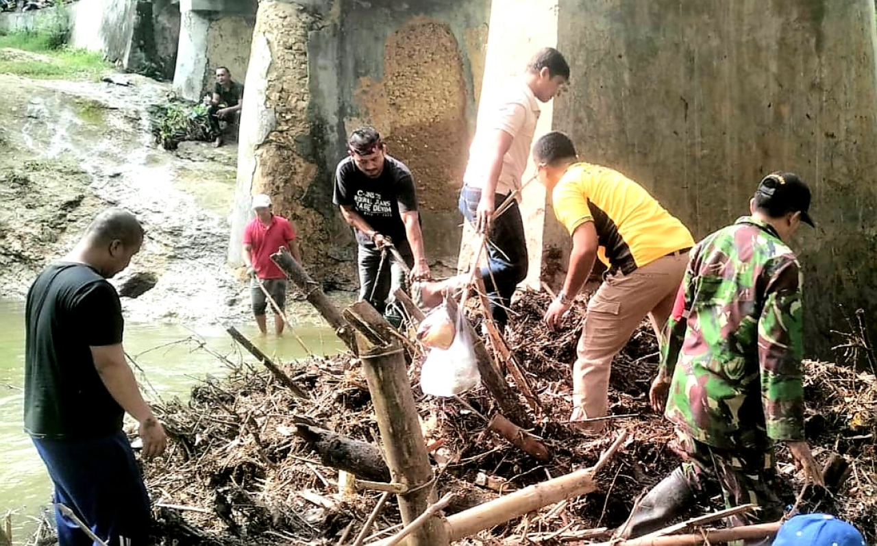Anggota Kodim 0829/Geger bersama Anggota Polsek dan masyarakat bahu membahu membersihkan sampah yang menyumbat saluran air (foto : pendim0829/hartono_beritaformat.com)
