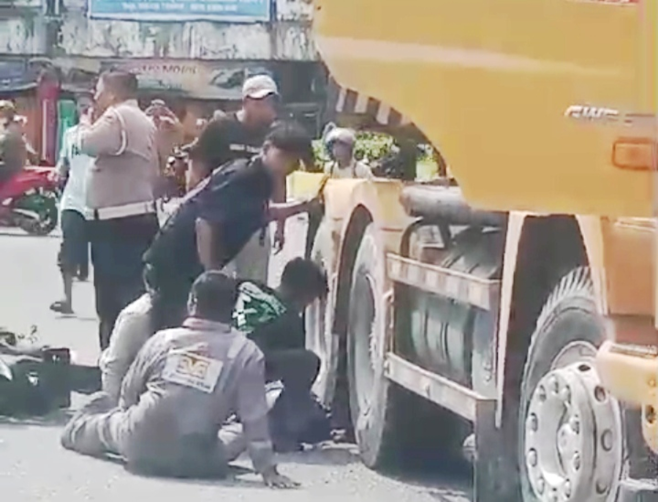 Warga membantu evakuasi korban laka lantas yang terjepit roda belakang trailer (foto : salahudin_beritaformat.com)