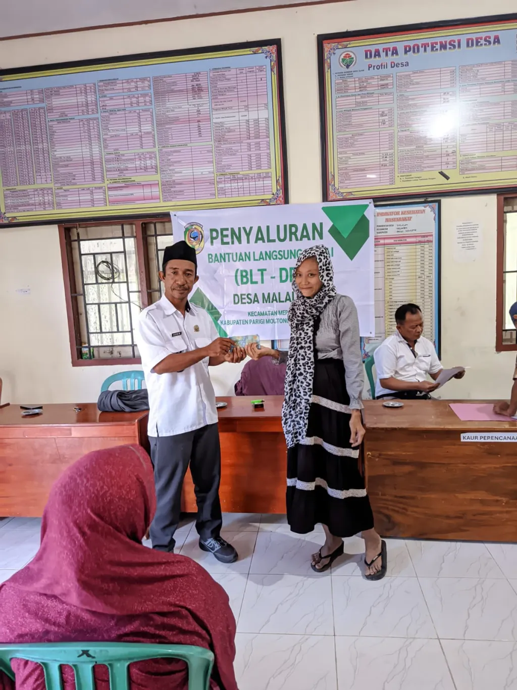 Secara simbolis, Kades Malalan memberikan BLT kepada warga yang sudah terverifikasi (foto : enos_beritaformat)